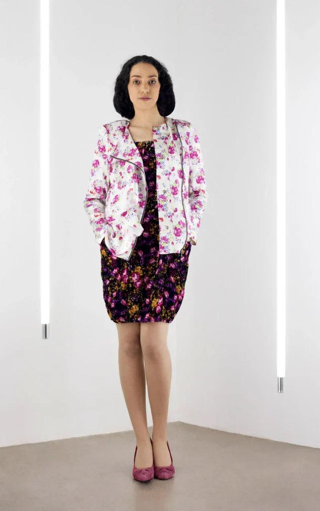 Model wearing a sixties-inspired French floral print biker jacket over a black silk velvet dress with a front zipper.